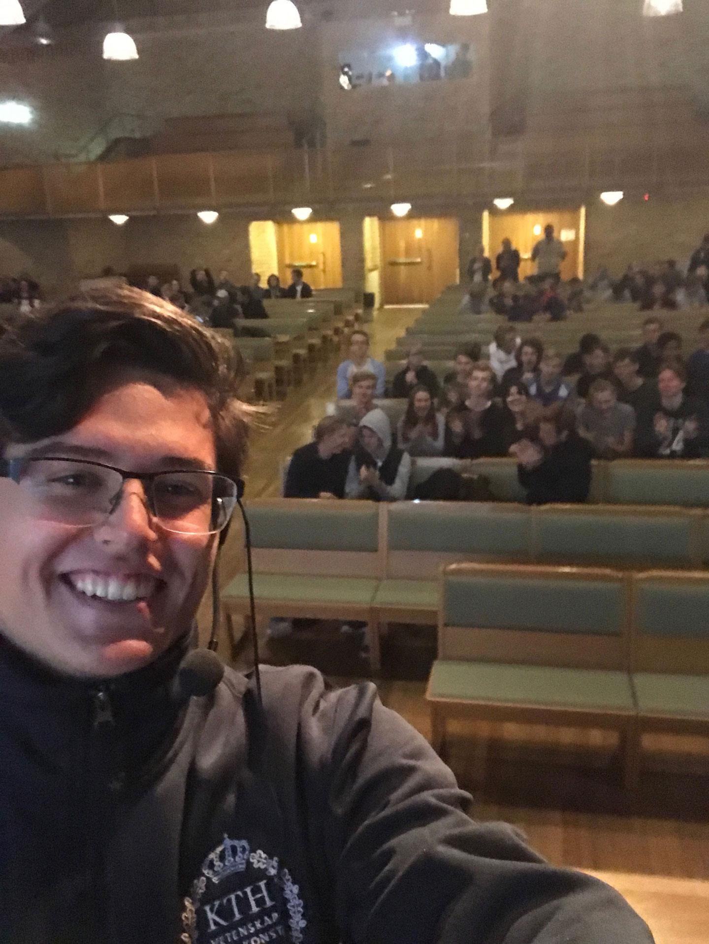 Smiling person taking a selfie in front of an audience in a lecture hall at Vägar vidare i Örnsköldsvik, Nolaskolan